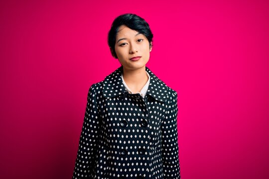 Young beautiful asian girl wearing casual jacket standing over isolated pink background looking sleepy and tired, exhausted for fatigue and hangover, lazy eyes in the morning.