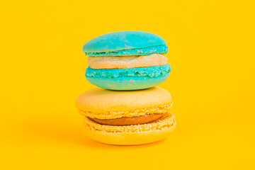 Sweet almond colorful unicorn blue yellow macaron or macaroon dessert cake isolated on trendy yellow modern fashion background. French sweet cookie. Minimal food bakery concept Copy space