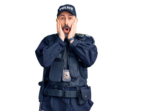 Young handsome man wearing police uniform afraid and shocked, surprise and amazed expression with hands on face