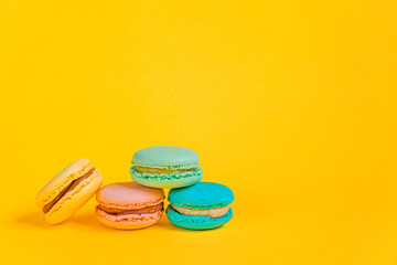 Sweet almond colorful unicorn pink blue yellow green macaron or macaroon dessert cake isolated on trendy yellow modern fashion background. French sweet cookie. Minimal food bakery concept Copy space