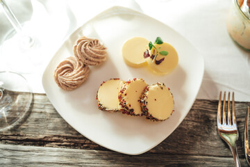 Top view of plate with several slices of flavored butters laying on wooden table with white tablecloth. Celebration, birthday or wedding concept.