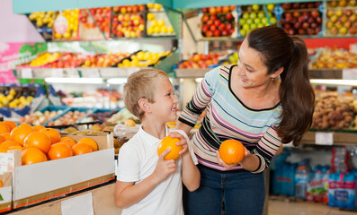 Fototapeta premium boy with woman choosing fresh oranges