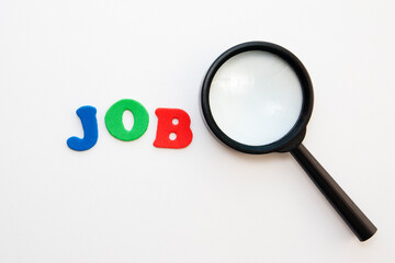 A magnifying glass near the word job done with letters on a white background, top view. Job Concept Search