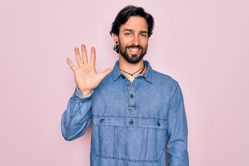 Young handsome hispanic bohemian man wearing hippie style over pink background showing and pointing...