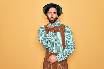 Young handsome man wearing tratidional german octoberfest custome for Germany festival looking at the camera blowing a kiss with hand on air being lovely and sexy. Love expression.