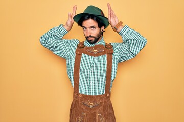 Young handsome man wearing tratidional german octoberfest custome for Germany festival Doing bunny ears gesture with hands palms looking cynical and skeptical. Easter rabbit concept.