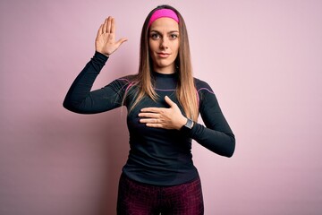 Young blonde fitness woman wearing sport workout clothes over isolated background Swearing with...