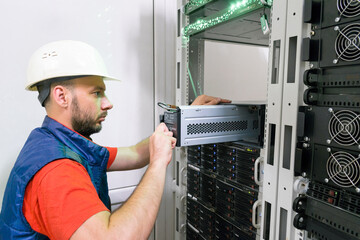 . Replacing the power module in the server room rack. Maintenance of data center equipment. The technician installs a new battery pack into the uninterruptible power supply