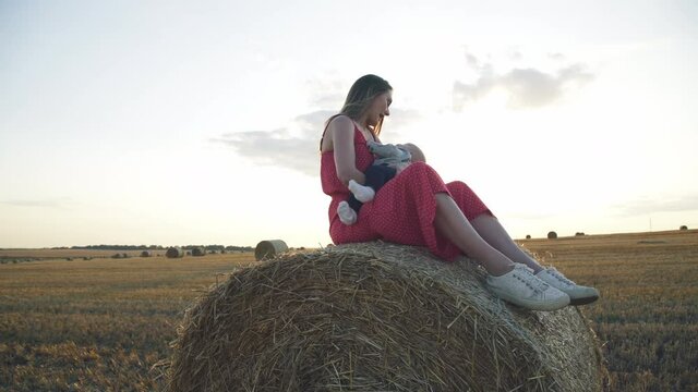 Young mother plays and has a fun with her baby son when relaxes on haystack