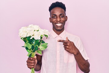 Young african american man holding flowers smiling happy pointing with hand and finger