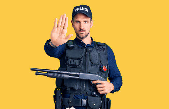 Young handsome man wearing police uniform holding shotgun stressed and frustrated with hand on head, surprised and angry face