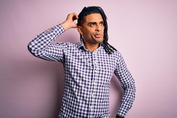 Young handsome african american afro man with dreadlocks wearing casual shirt confuse and wondering...