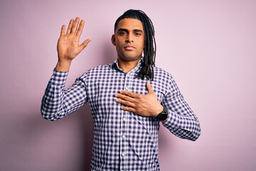 Young handsome african american afro man with dreadlocks wearing casual shirt Swearing with hand on...
