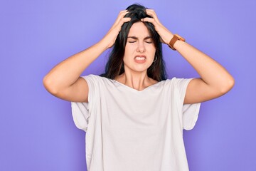Obraz na płótnie Canvas Young beautiful brunette woman wearing casual white t-shirt over purple background suffering from headache desperate and stressed because pain and migraine. Hands on head.