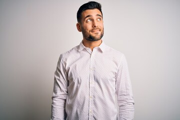 Young handsome man wearing elegant shirt standing over isolated white background smiling looking to the side and staring away thinking.