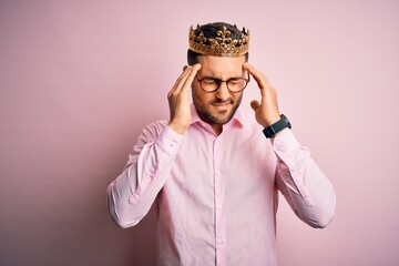 Young handsome business man wearing golden crown as king over pink background suffering from headache desperate and stressed because pain and migraine. Hands on head.