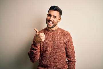 Young handsome man wearing casual sweater standing over isolated white background doing happy...