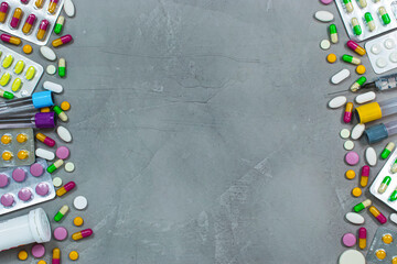 Background with medicine, pills and syringes around the gray floor with copy space in the middle.