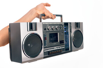 Hand of caucasian young man holding vintage radio cassette over isolated white background