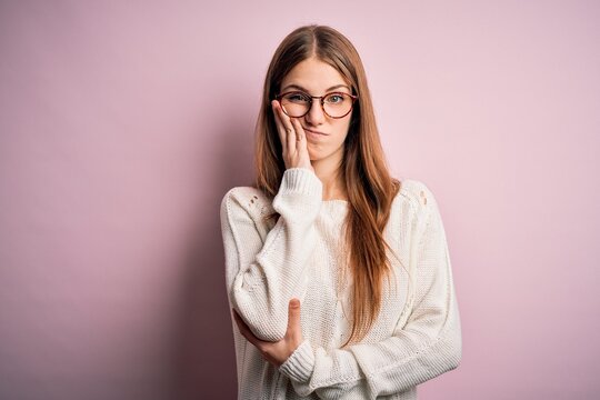 Young beautiful redhead woman wearing casual sweater and glasses over pink background thinking looking tired and bored with depression problems with crossed arms.