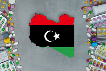 The Libya State began research for treatment and medicine to combat the pandemic outbreak disease coronavirus. Medicine, pills, needles, syringes and Libya map and flag on gray background.
