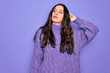 Fototapeta premium Young beautiful woman wearing casual turtleneck sweater standing over purple background confuse and wondering about question. Uncertain with doubt, thinking with hand on head. Pensive concept.