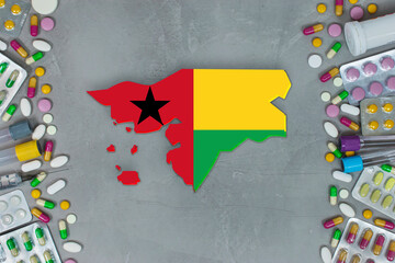 The Gine Bissau State began research for treatment and medicine to combat the pandemic outbreak disease coronavirus. Medicine, pills, needles, syringes and Gine Bissau map and flag on gray background.