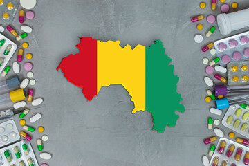 The Guinea State began research for treatment and medicine to combat the pandemic outbreak disease coronavirus. Medicine, pills, needles, syringes and Guinea map and flag on gray background.