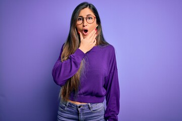 Young beautiful smart woman wearing glasses over purple isolated background Looking fascinated with disbelief, surprise and amazed expression with hands on chin