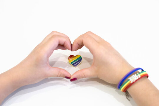 Female heart shaped hands over rainbow heart-shaped icon on white background