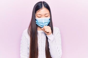 Young beautiful chinese woman wearing medical mask feeling unwell and coughing as symptom for cold or bronchitis. health care concept.