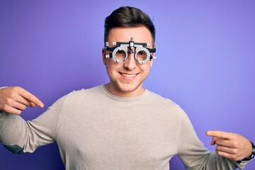 Young handsome caucasian man wearing optometrical glasses over purple background looking confident with smile on face, pointing oneself with fingers proud and happy.