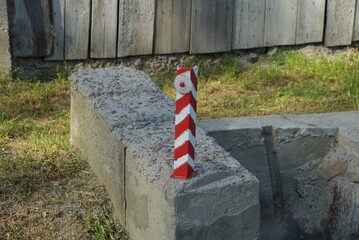 one striped iron pole limiter with a reflector on a gray concrete block on the street by the road