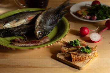 toast with salted fish and chopped parsley and a plate of dried roach on a wooden table