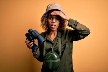 African american tourist woman wearing explorer hat and water canteen holding binoculars stressed...