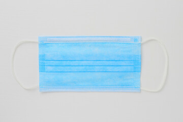 Classical medical surgical mask. The main symbol of the covid-19 pandemic. White wood background....