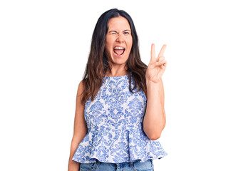 Young beautiful brunette woman wearing casual t-shirt smiling with happy face winking at the camera doing victory sign. number two.