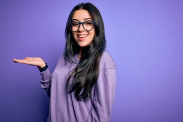 Young brunette woman wearing glasses over purple isolated background smiling cheerful presenting...