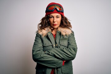 Middle age skier woman wearing snow sportswear and ski goggles over white background skeptic and nervous, disapproving expression on face with crossed arms. Negative person.