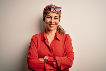 Middle age brunette woman wearing handkerchief on head and shirt over white background happy face smiling with crossed arms looking at the camera. Positive person.