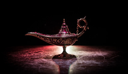 Lamp of wishes concept. Antique Aladdin arabian nights genie style oil lamp with soft light white...