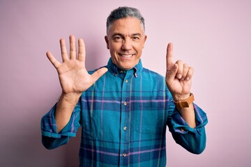 Middle age handsome grey-haired man wearing casual shirt over isolated pink background showing and pointing up with fingers number six while smiling confident and happy.