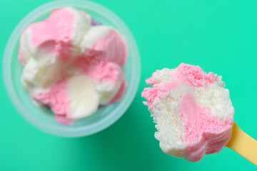 eating cup of strawberry flavor ice cream on green background