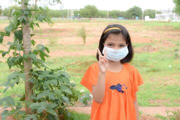 indiaLittle girl has face mask protect herself from Coronavirus,New Normal child leave the house with a mask on her nose for safety outdoor activity after COVID-19 outbreak,illness or Air pollution
