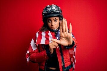 African american patriotic motorcyclist girl wearing moto helmet wearing united states flag with open hand doing stop sign with serious and confident expression, defense gesture