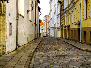 Fototapeta na wymiar Selectife focus. Street And Old Town Architecture in Tallinn, Estonia. Old stone paved avenue street road. Cobble stones, low angle shot of wet old pavement. filtered or toned image. copy space