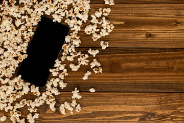 Modern tablet computer on wooden floor, black screen and blank, surrounded by popcorn. Besides copy space. Mockup phone with black copy space.