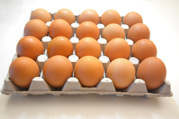 20 brown eggs in a carton box. Original look, eggs of a different shade. Light gray cardboard stand with eggs on a white background. and Idea for breakfast and cooking