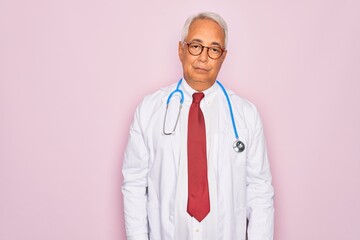 Middle age senior grey-haired doctor man wearing stethoscope and professional medical coat looking...