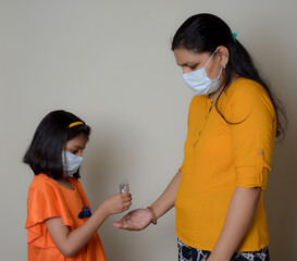 indian little girl is helping her mother to sanitize his hands. due to Covid-19 pandemic